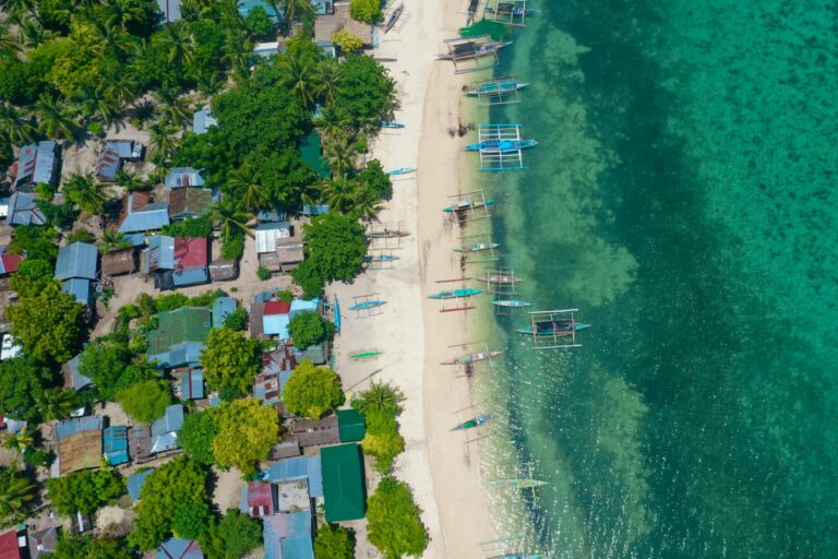 A stunning aerial view of a coastal village with vibrant boats along the shore in the Philippines.