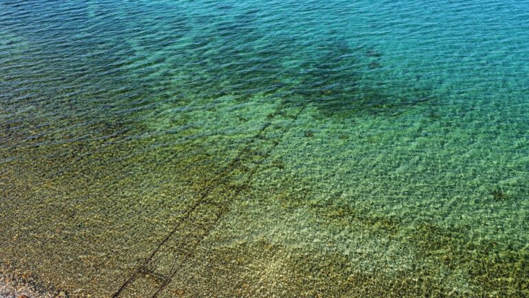 A mesmerizing view of crystal clear ocean water with a rocky seabed in turquoise hues.