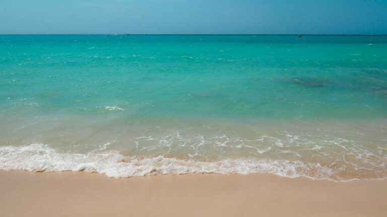 Serene beach scene with turquoise waves and sandy shore, perfect for relaxation imagery.