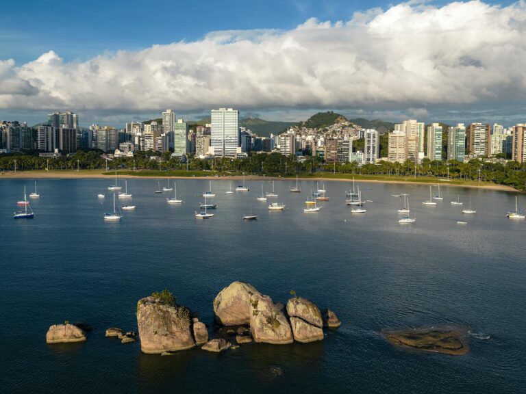 Aerial view of sailboats near Ilha do Frade with a backdrop of Vitoria, Brazil cityscape.