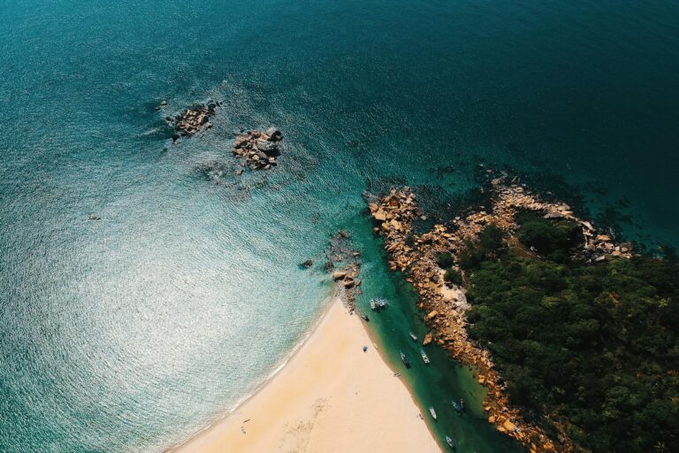 Stunning aerial view of a tropical beach with turquoise waters and rocky shoreline, perfect for travel and nature enthusiasts.