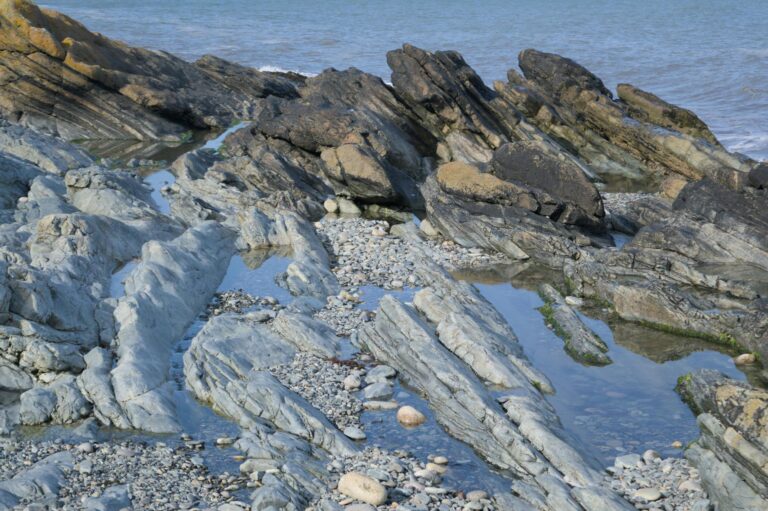 Explore the rugged rocky shoreline of Newcastle, Northern Ireland with clear ocean views.