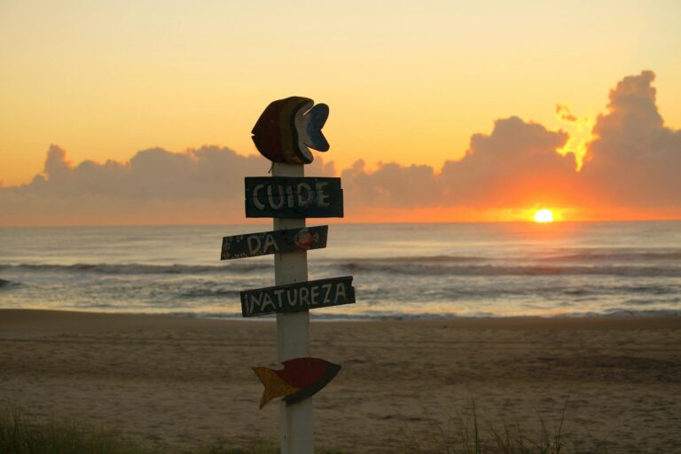 Beautiful sunrise at Guaratuba Beach, Brazil with nature-themed signs urging environmental care.