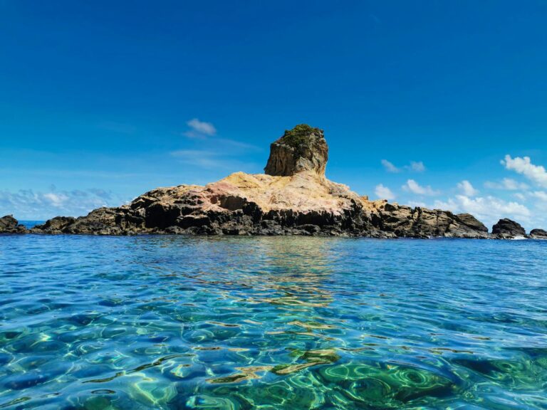 Breathtaking view of a rock formation surrounded by clear blue sea and sky.