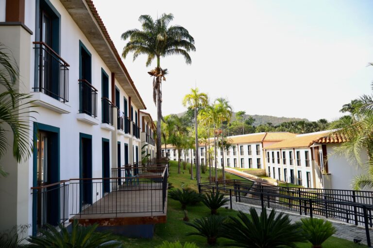 Modern resort buildings with palm trees under clear skies.