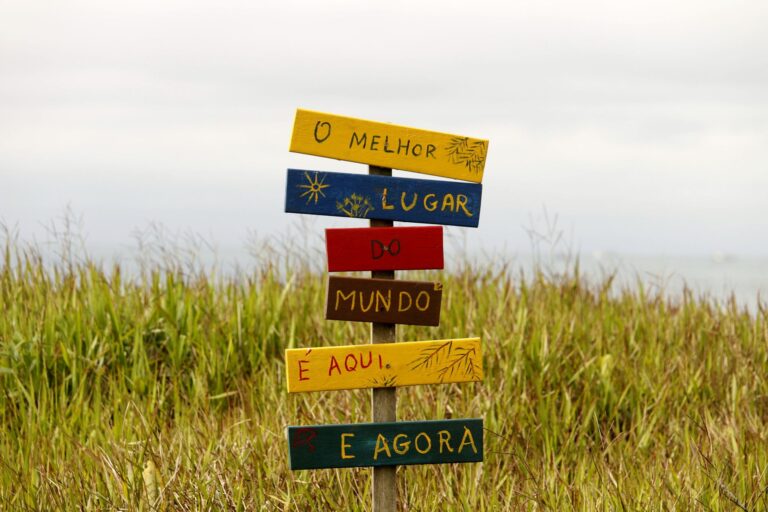 Vibrant multilingual sign in a grassy field in Guaratuba, Paraná, Brazil, showcasing local charm.
