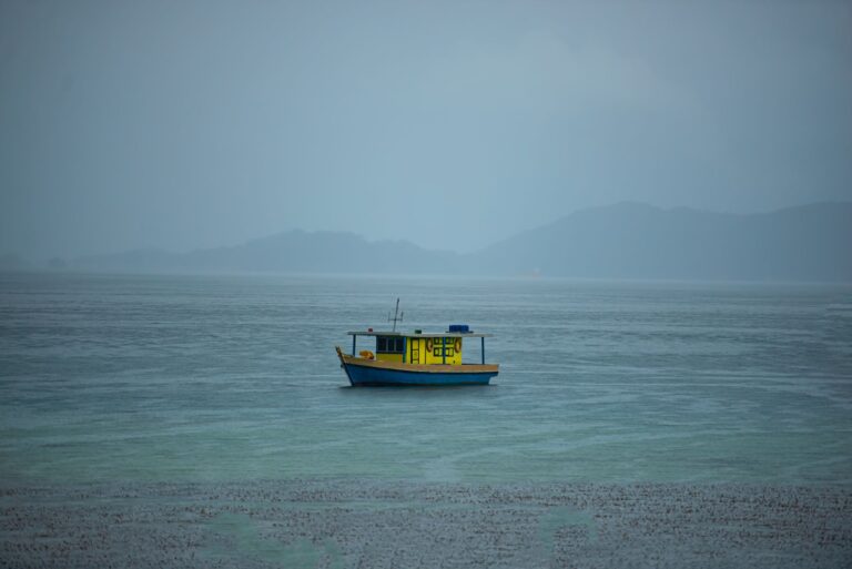 A yellow boat floats on the tranquil sea near Tuaran, Sabah, Malaysia, under a clear sky.