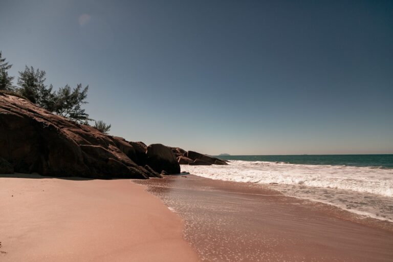 Peaceful beach scene in Florianópolis, Brazil with calm waves and a clear blue sky.