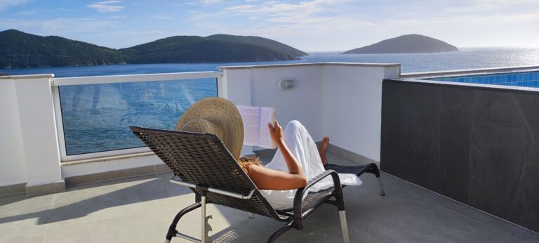 Woman reading on a terrace with stunning ocean views in Arraial do Cabo, Brazil.