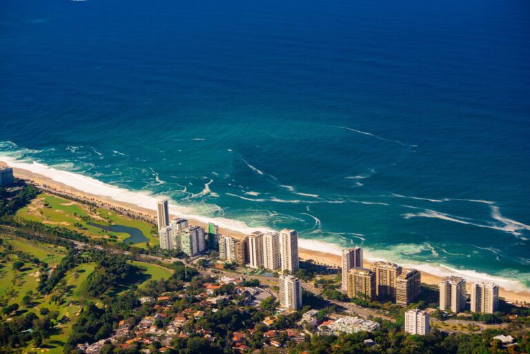 Stunning aerial view of Rio de Janeiro's coastline with skyscrapers and ocean waves.