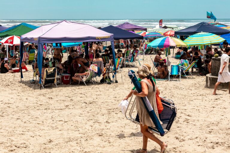 Lively beach scene filled with people, umbrellas, and tents on a sunny day.