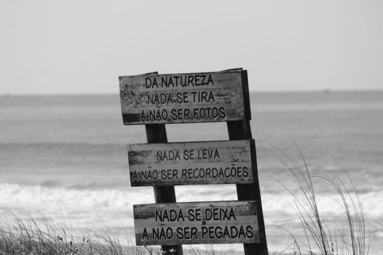 Black and white image of a sign with inspirational message on a beach.