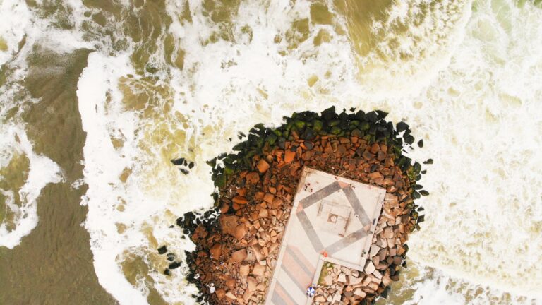 A stunning aerial shot capturing a rocky pier surrounded by ocean waves in Rio de Janeiro, Brazil.