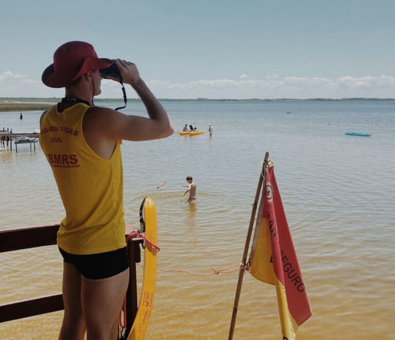 A woman in a yellow shirt and hat standing on a beach
