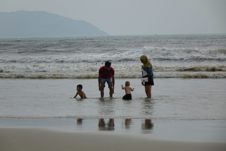 A group of people standing on top of a beach next to the ocean