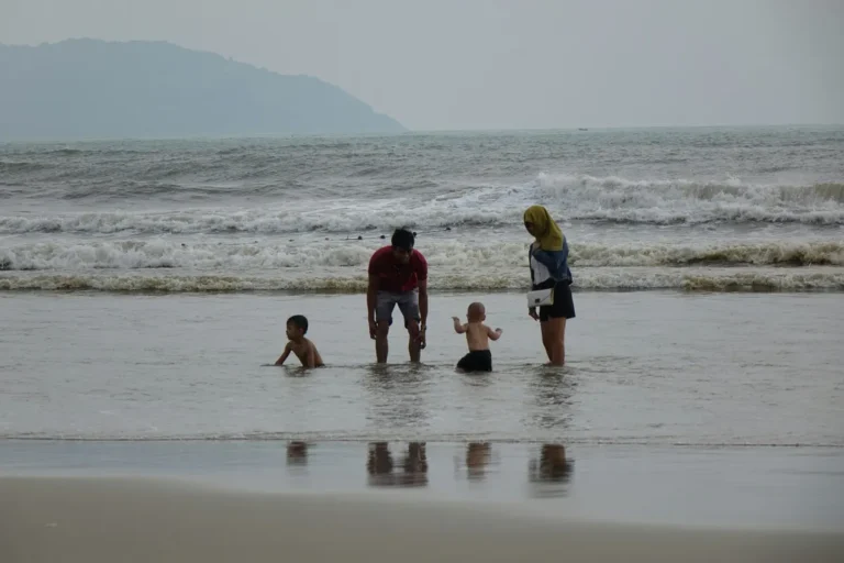 A group of people standing on top of a beach next to the ocean