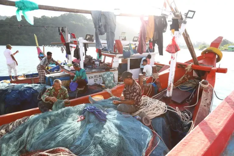 Fishermen working at sunrise on vibrant boats in Aceh, showcasing local culture.