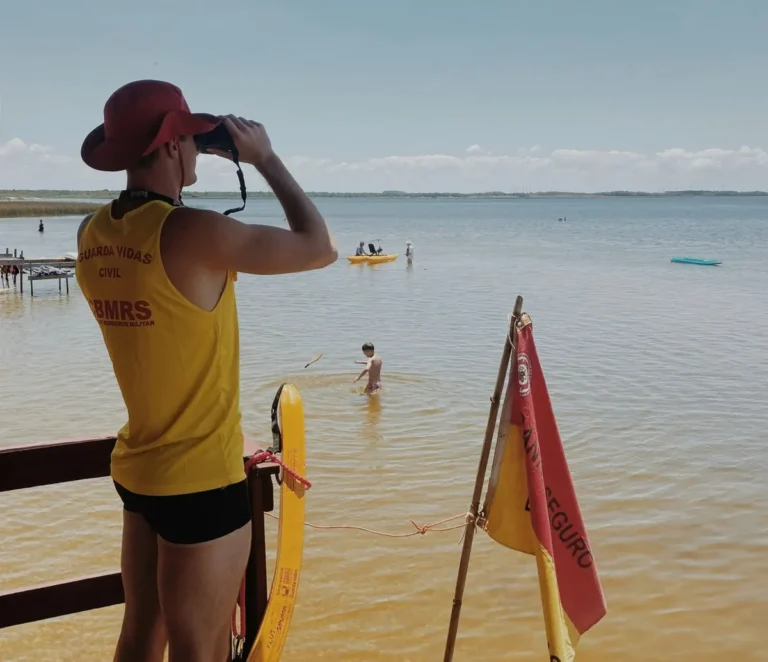 A woman in a yellow shirt and hat standing on a beach