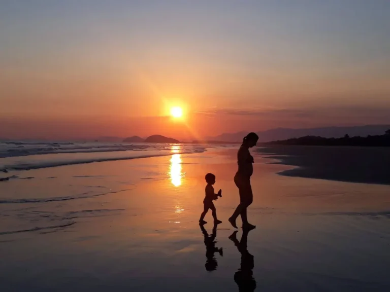 A serene sunset on São Sebastião beach with two silhouettes walking along the shore.